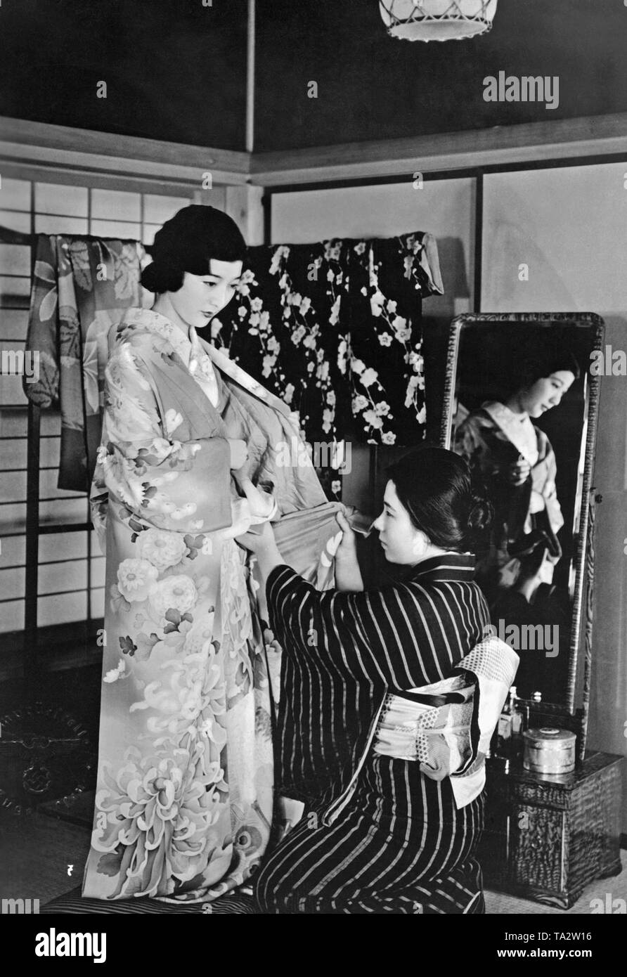 Un serviteur vient en aide à une jeune femme au Japon pour mettre sur son kimono. (Photo non datée), ch. 1940) Banque D'Images