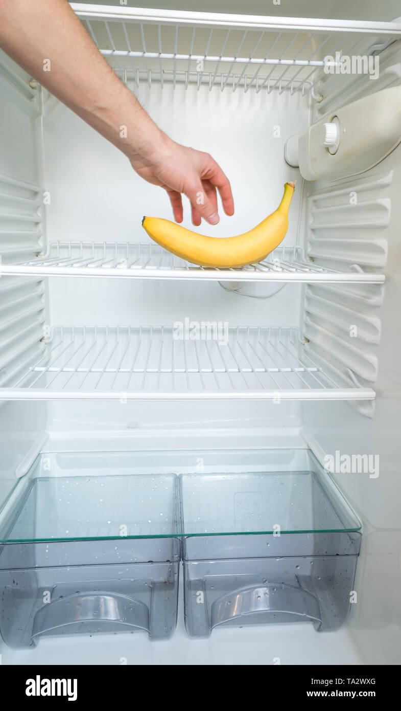 La main d'un homme atteint d'une banane dans un esprit d'ouverture,  réfrigérateur vide. Concept de régime de perte de poids Photo Stock - Alamy