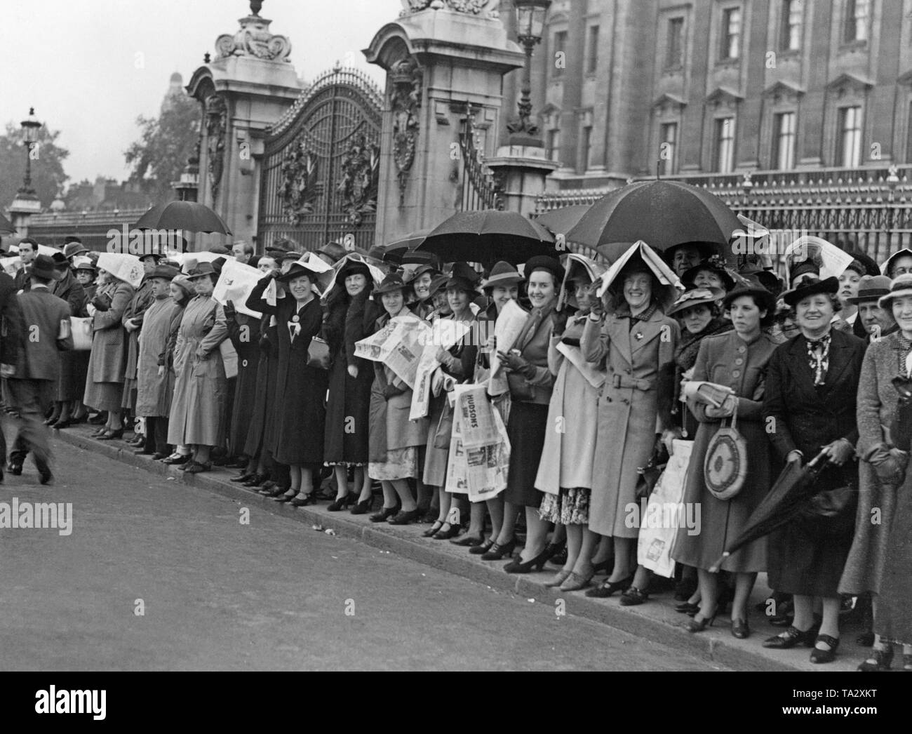 Les gens attendent sur le bord de la route devant le palais de Buckingham à Londres. Le Premier ministre britannique revient de Munich, et des lecteurs pour le monarque britannique. Un accord a été conclu avec Hitler à Munich. C'était censé l'annexe les Sudètes à l'Empire allemand sans commencer une guerre. Banque D'Images