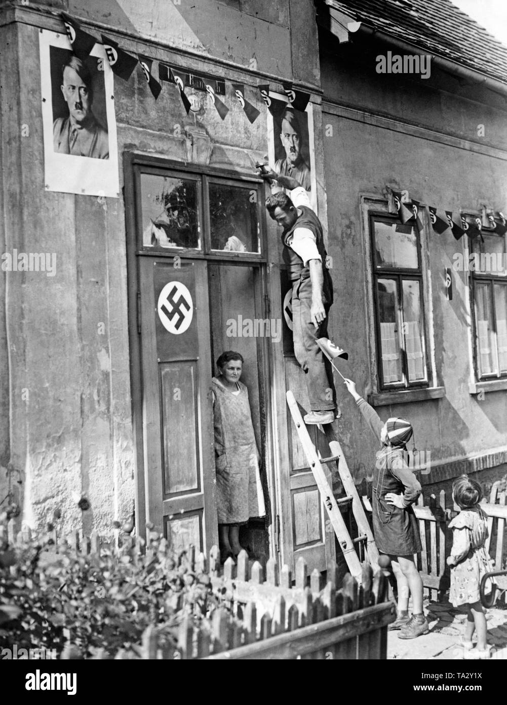 Résidents d'une maison à Rumburk fixez croix gammée des drapeaux et des portraits d'Hitler à leur mur de la maison le 30 septembre 1938, en l'honneur de l'invasion des troupes allemandes pendant l'occupation des Sudètes. Banque D'Images