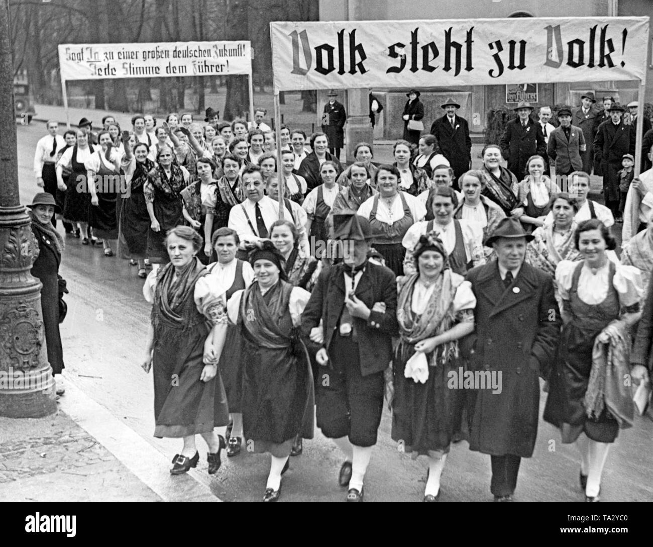 Un costume national à l'en-tête de groupe Emplacement du scrutin à l'élection partielle des élections du Reichstag en Cheb, Sudètes, le 4 décembre 1938. Ils portent des banderoles avec les inscriptions "peuple à la hauteur des personnes !' et 'Say yes pour un grand avenir allemand ! Tout le monde vote pour le Führer ! ' Banque D'Images