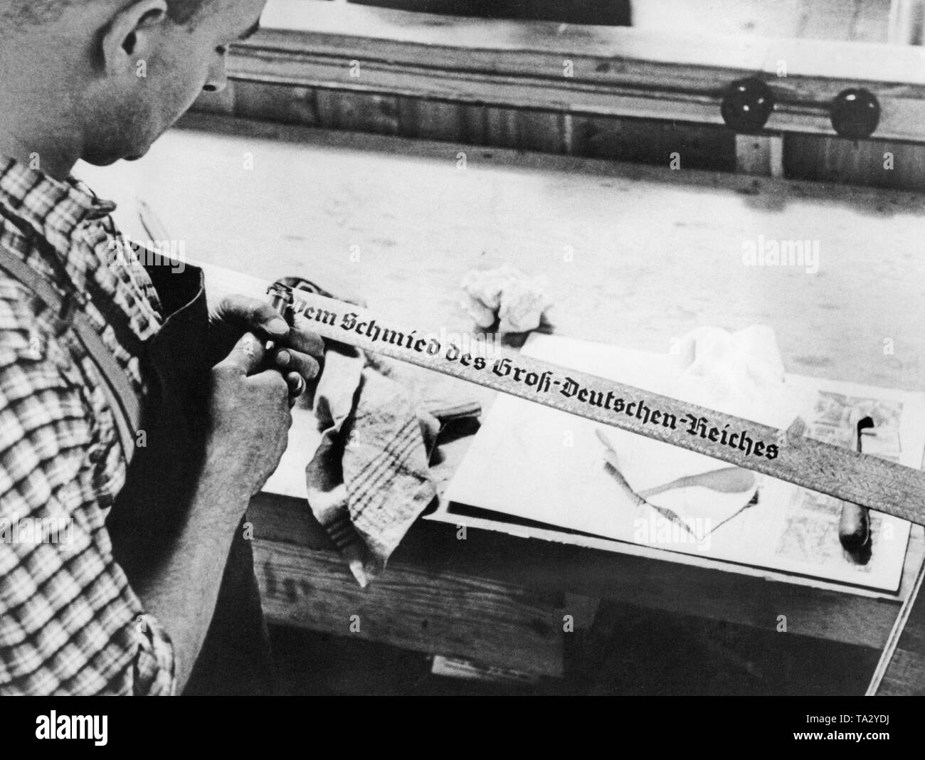 Un fabriquant de produits à polir une épée. L'épée est un don pour Adolf Hitler de la Deutschen Handwerk. La gravure se lit comme suit : "Pour le forgeron du grand Reich allemand". Banque D'Images
