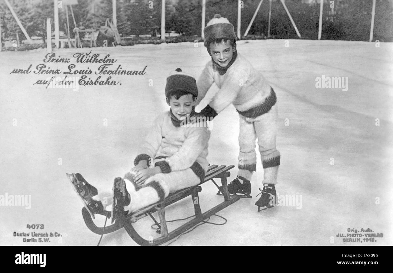 Prince héréditaire Wilhelm (gauche) assis avec son jeune frère le prince Louis Ferdinand (droit debout) sur une patinoire. Les deux princes porter des patins à glace. Le Prince Wilhelm est assis sur un traîneau en bois, Prince Louis Ferdinand repose sur les épaules de son frère. Banque D'Images