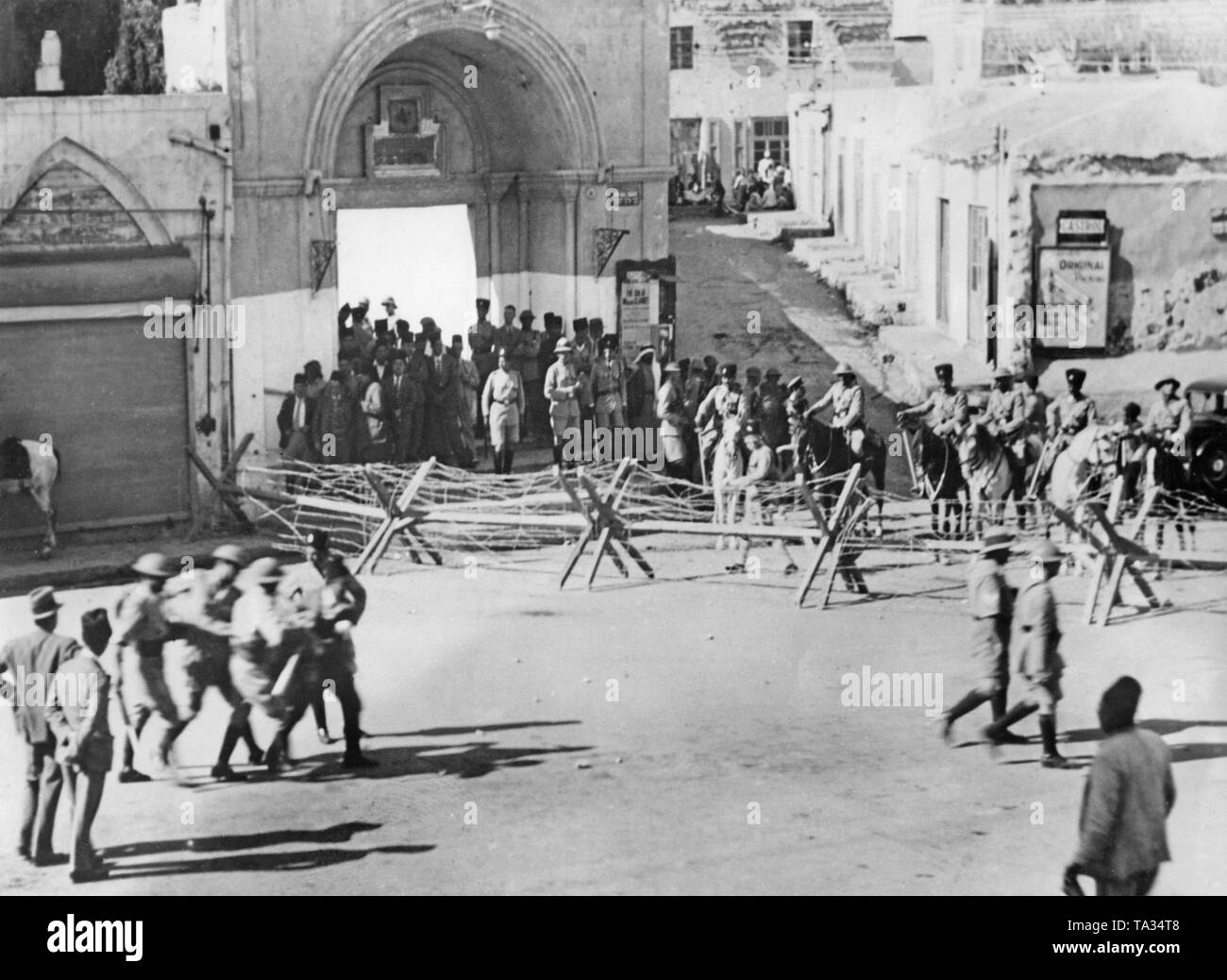 Les forces de sécurité britannique à Jaffa, lutter contre les protestations de la population arabe. Ici, c'est un barrage routier ainsi qu'un policier blessé, qui est emporté par ses collègues (avant gauche). Banque D'Images