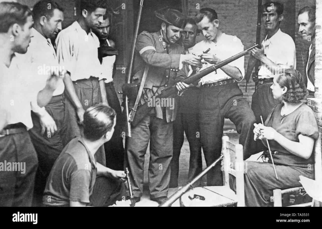 Un membre (au centre) de la Guardia Civil (une unité de police paramilitaire, qui rejoint presque entièrement les troupes de Franco en 1936, forme des milices de la défense civile et d'une femme sur la manipulation d'une carabine. Le policier montre le milicien le verrou retiré de l'arme. Banque D'Images