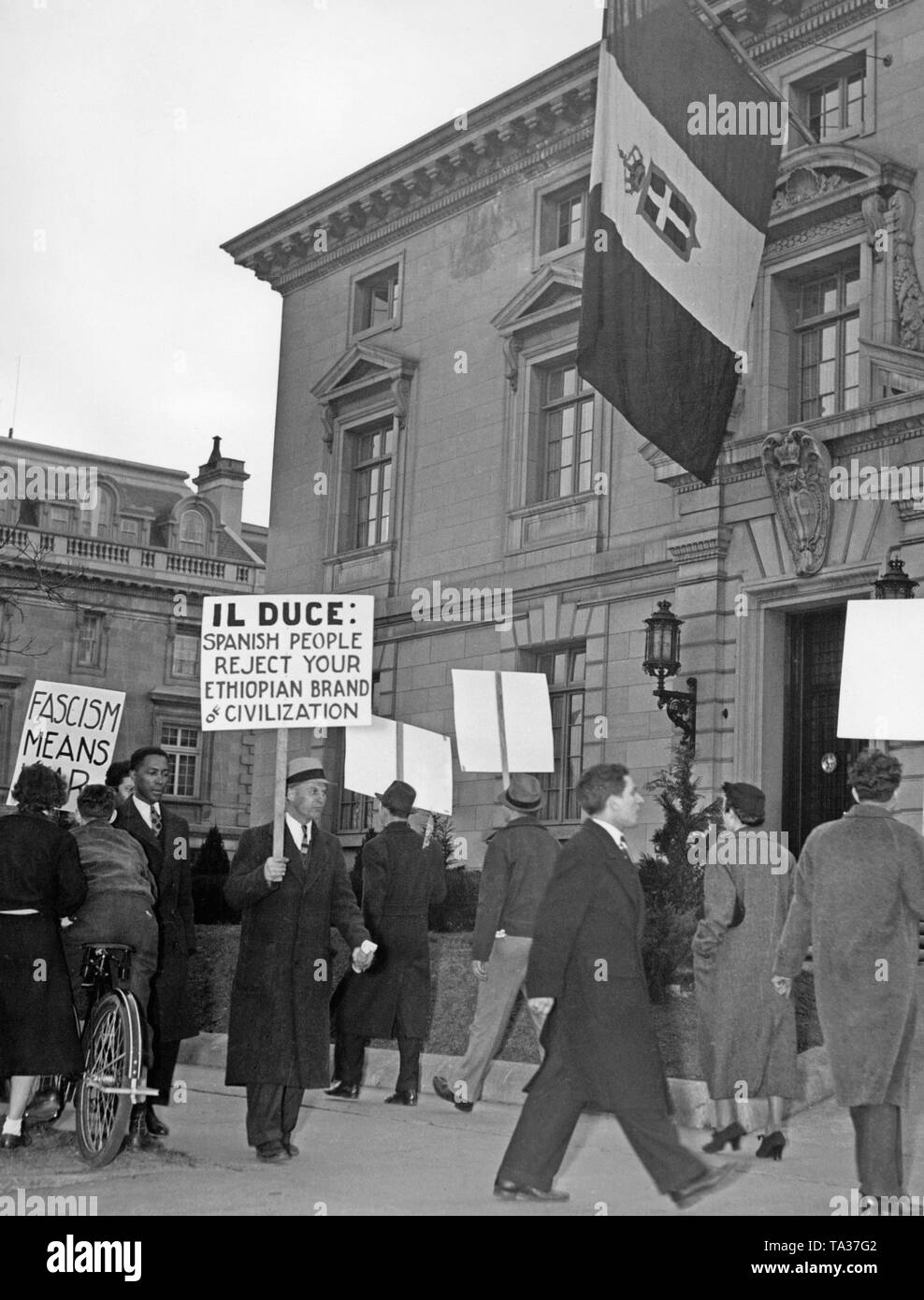 Photo d'un groupe de travailleurs de manifester devant l'ambassade italienne (16e Rue coin de Fuller Street) à Washington DC contre l'appui de la national espagnol par les troupes de l'armée italienne. Les manifestants ont des banderoles avec les inscriptions : 'fascisme signifie la guerre". Dans l'arrière-plan, le drapeau du Royaume d'Italie. Banque D'Images