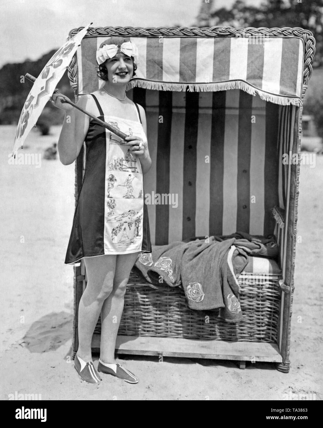 Femme à côté d'une chaise de plage dans une plage robe faite de jersey de soie noir et blanc. Banque D'Images