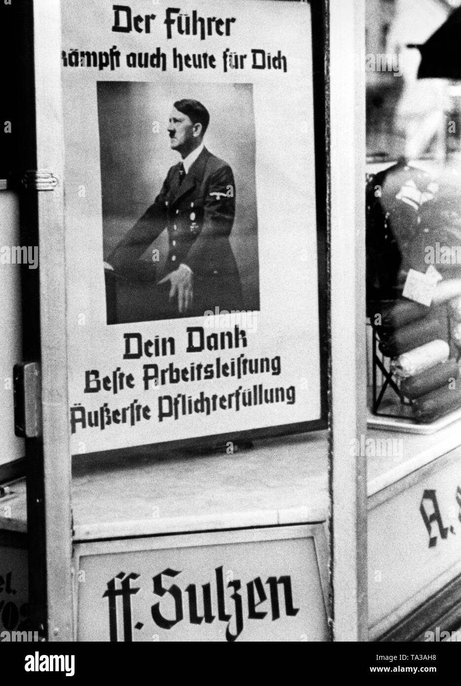 L'affiche de propagande à l'image d'Adolf Hitler et l'appeler "Le führer se bat pour vous même aujourd'hui. Votre reconnaissance est le meilleur travail et la performance de votre devoir' dans la vitrine d'un commerce de vente de textiles. Banque D'Images