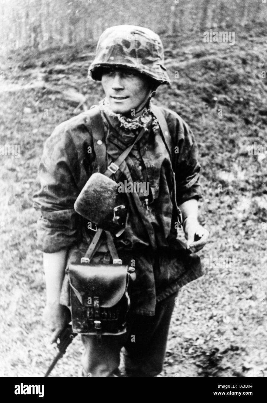 Un officier de la Waffen-SS avec une cigarette avant la prochaine attaque. Il est titulaire d'un Luger pistolet 08. Banque D'Images