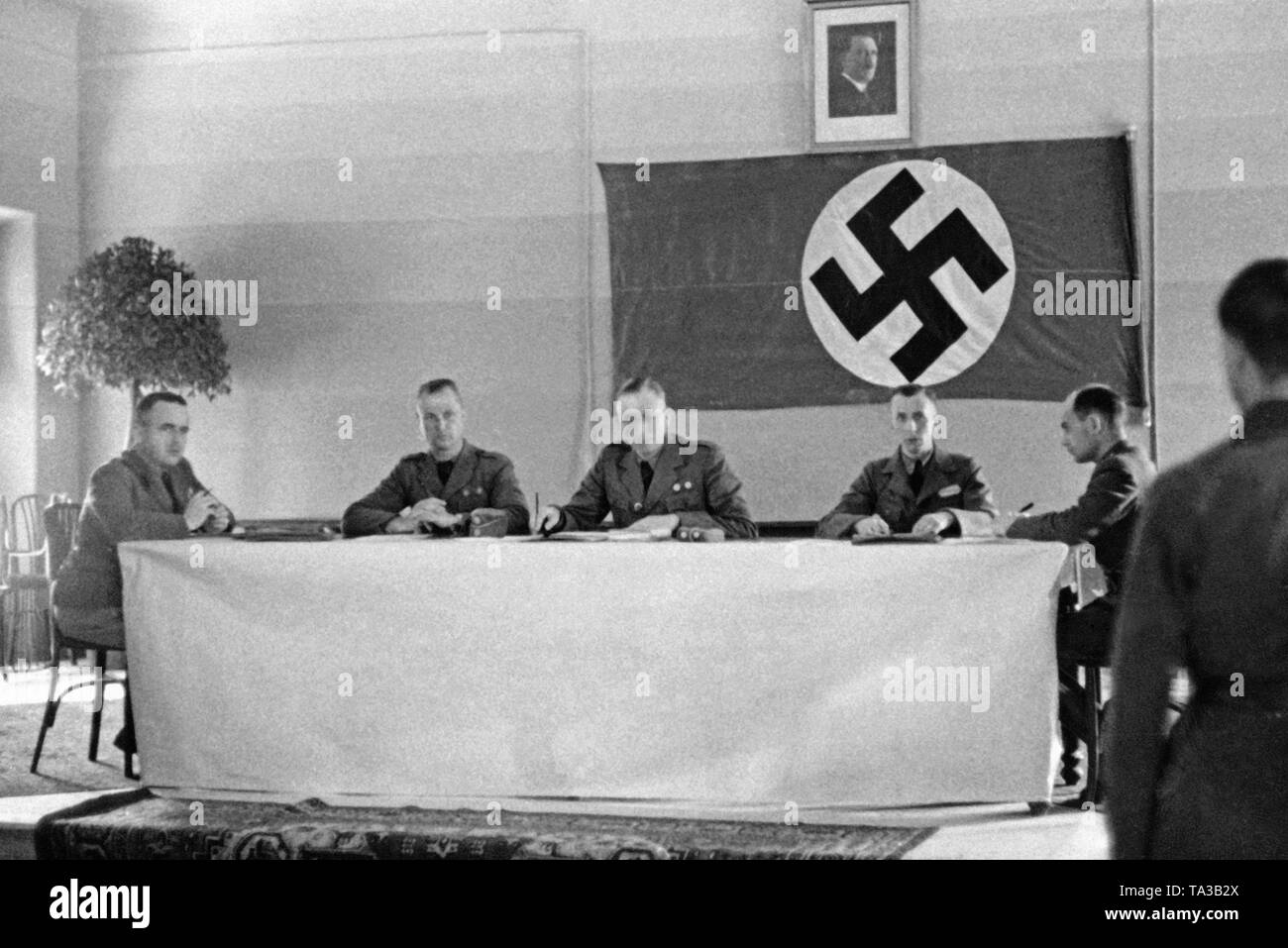 Photo non datée des trois leaders (de gauche à droite) : lieutenant, le colonel, le caporal avec dragonne cordon et l'évaluateur d'un tribunal militaire de la légion Condor allemande pendant la Guerre Civile Espagnole en 1939. Dans l'arrière-plan, un drapeau à croix gammée et un portrait d'Adolf Hitler. Banque D'Images