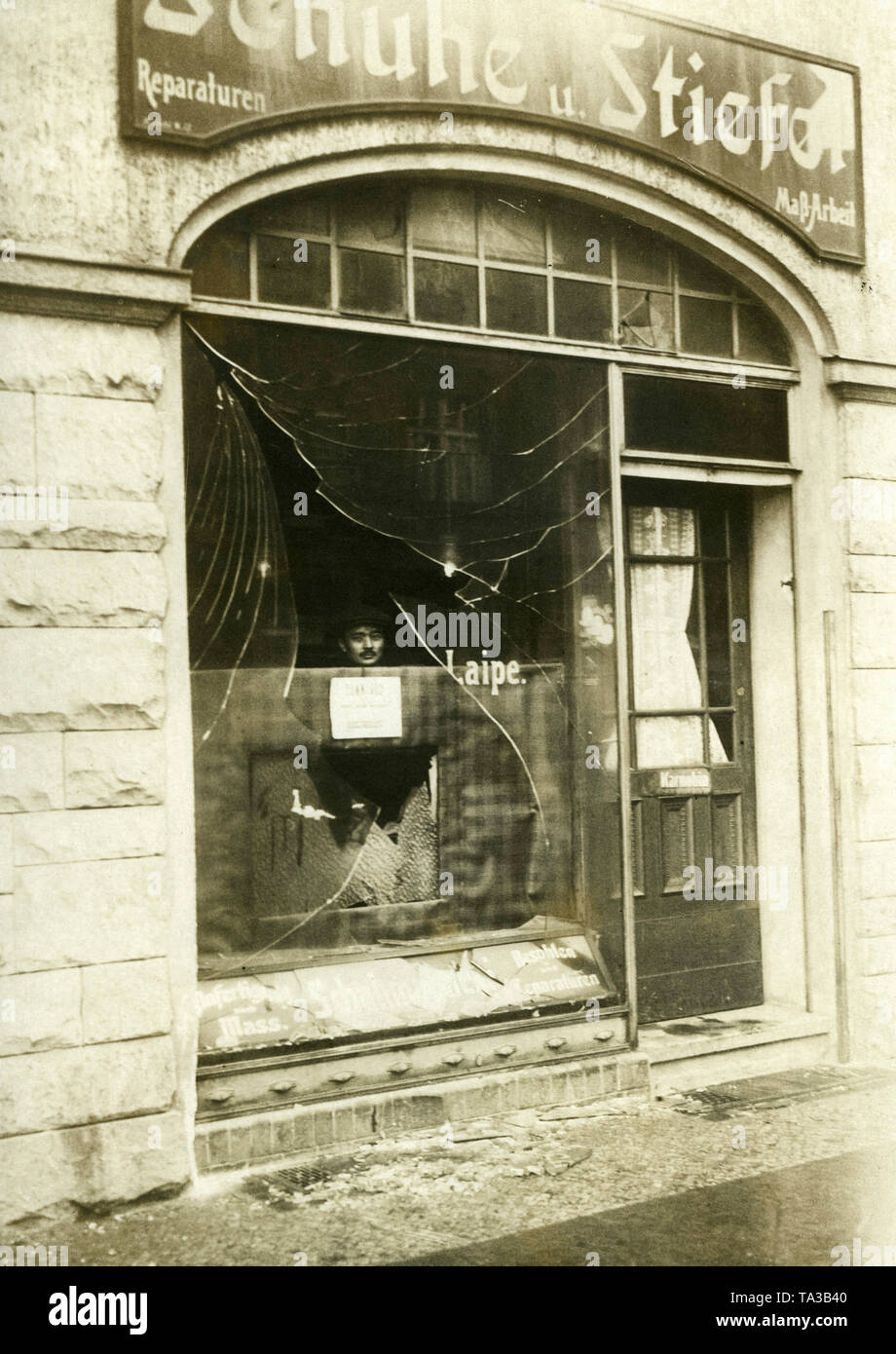 Un homme regarde à travers la vitrine brisée de la Laipe magasin de chaussures. La vitrine a été pillé probablement pendant les troubles à Berlin. Banque D'Images