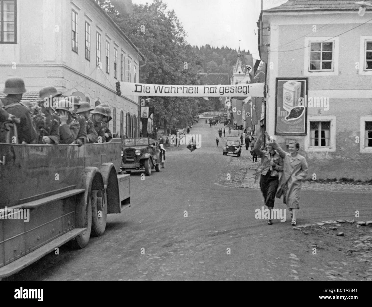 Les troupes allemandes en mars Oberplan Horni Plana (République tchèque) le 11 octobre 1938. Deux passants salue avec le salut nazi. Au-dessus de la rue est une bannière : "La Vérité a triomphé". Banque D'Images