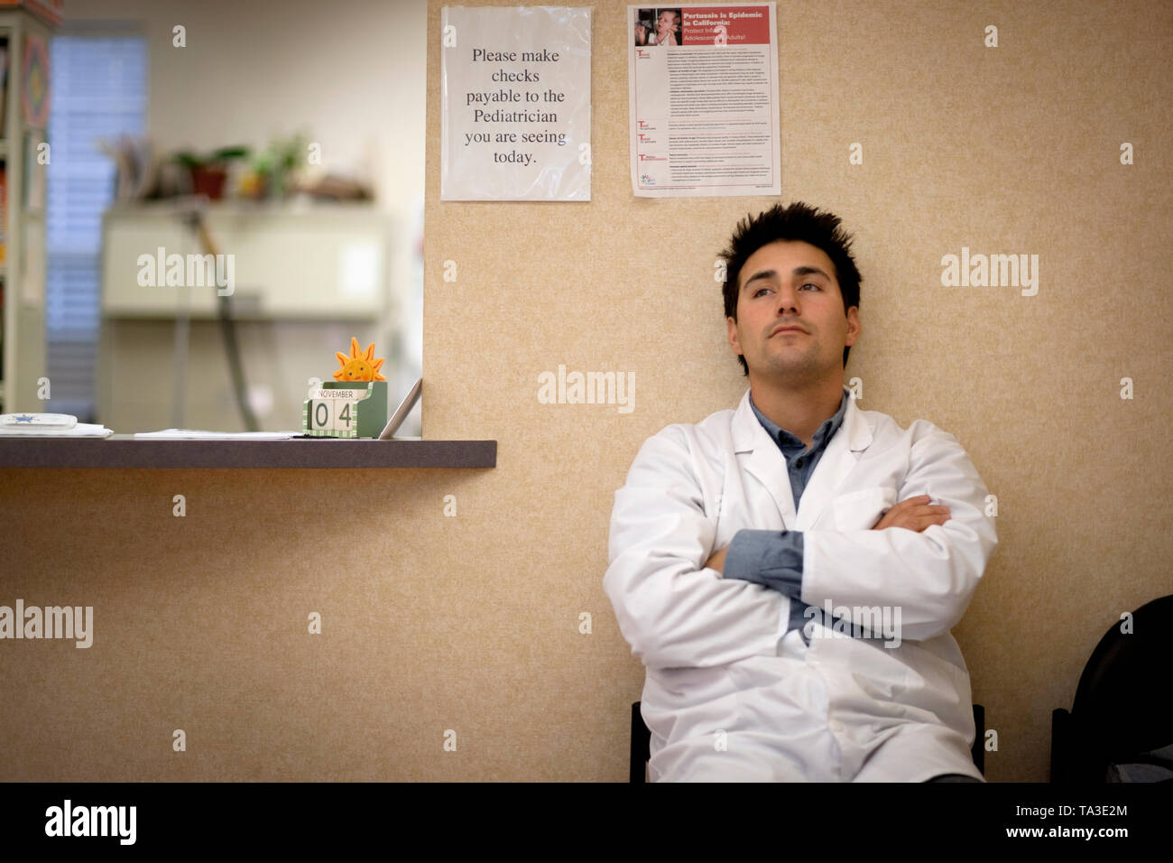 Anxieux médecin assis et d'attendre en face de son bureau. Banque D'Images