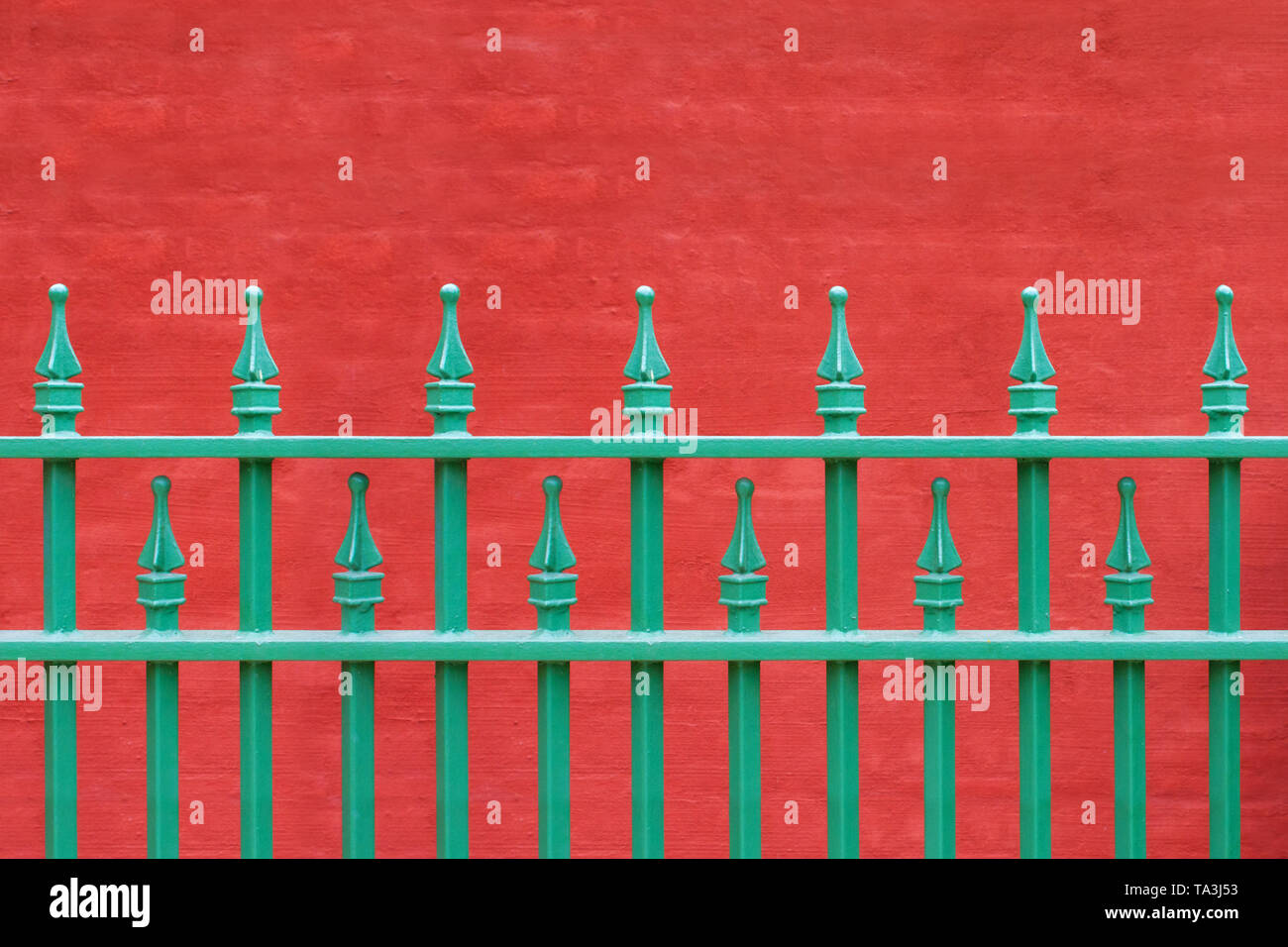 Clôture de fer de la tige en vert sur fond rouge Banque D'Images
