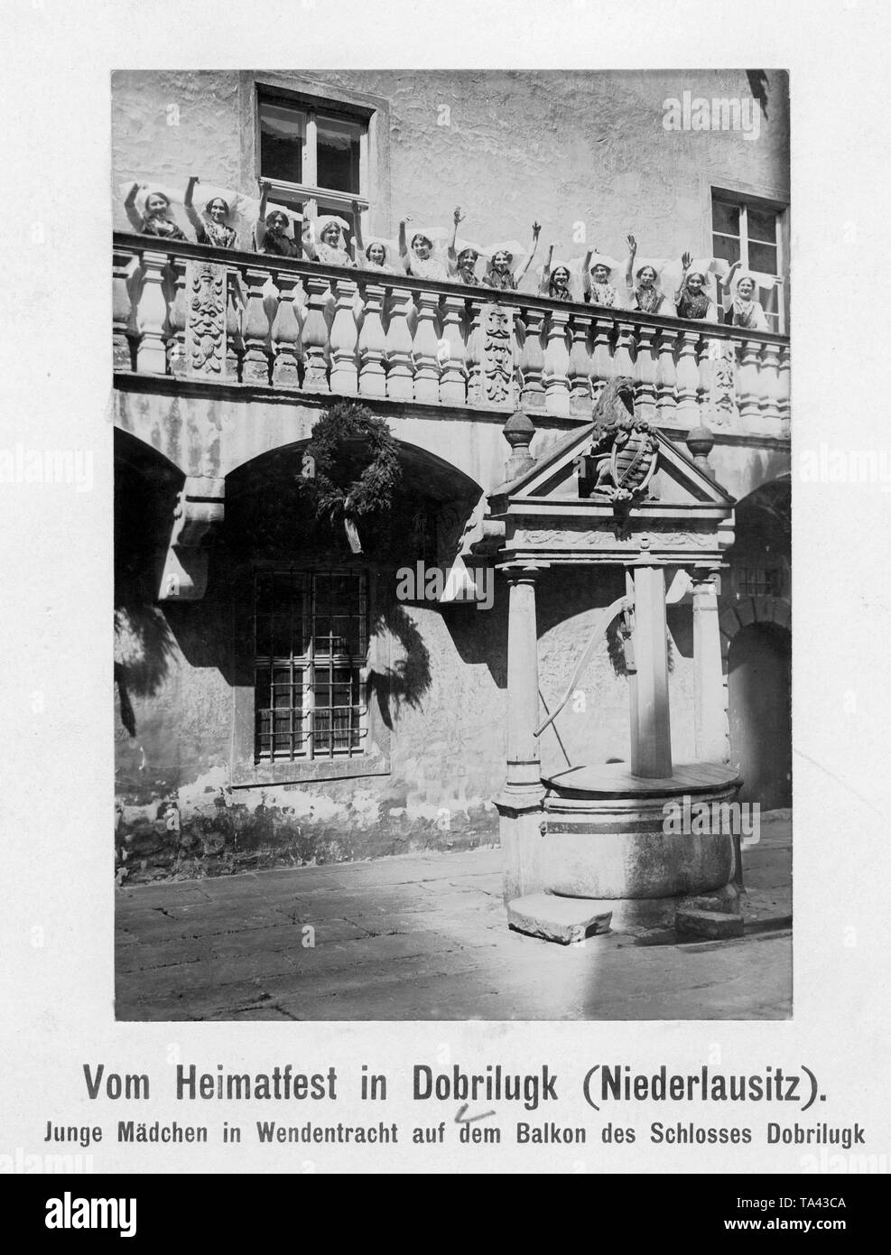 Les jeunes femmes en robes traditionnelles ou Wende forme depuis le balcon du château, Niederlausitz Dobrilugk, la Prusse. Au puits, les armoiries des ducs et rois de Saxe. La photo a été faite à l'occasion de l'Heimatfest wende. Banque D'Images