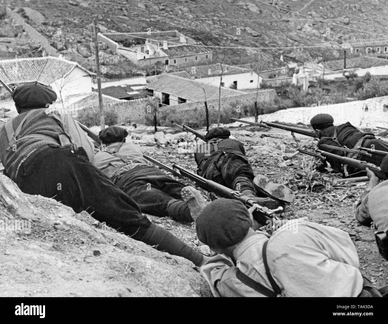 Les soldats espagnols se cachent avec des mousquetons et des baïonnettes dans une position sur une colline au-dessus d'un village près de Madrid pendant la bataille de Madrid, 1937. Les soldats porter des vêtements civils : culottes, puttees, simple cloué des bottes, des chandails et des bérets rouges. Banque D'Images