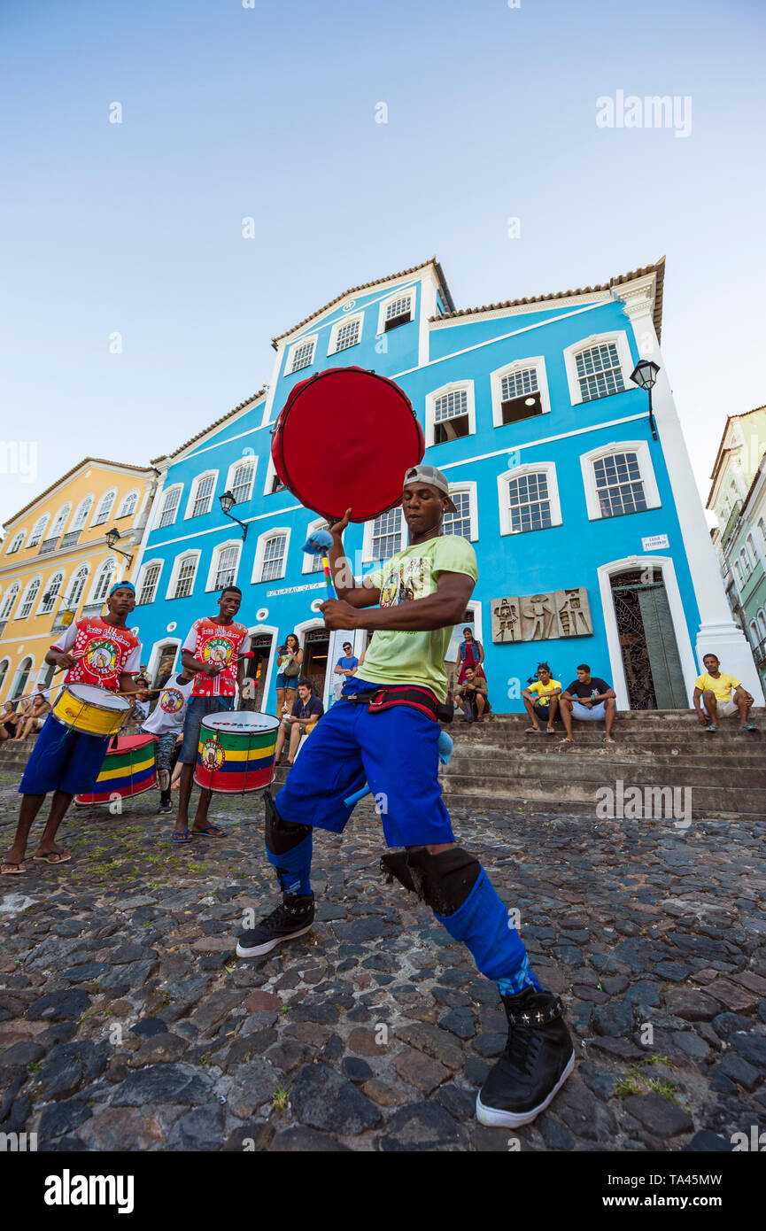 SALVADOR, BRÉSIL - Mars, 2018 : un batteur joue avec son en face de l'architecture coloniale colorée de Pelourinho, dans le cadre d'un projet social. Banque D'Images