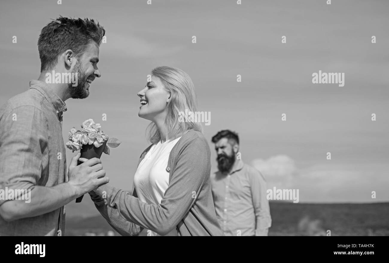 Nouvel amour. Ex-partenaire fille commence à regarder les relations amour heureux. Couple in love dating une journée ensoleillée, le fond de ciel. Couple avec fleurs bouquet date romantique. Ex mari jaloux sur l'arrière-plan. Banque D'Images