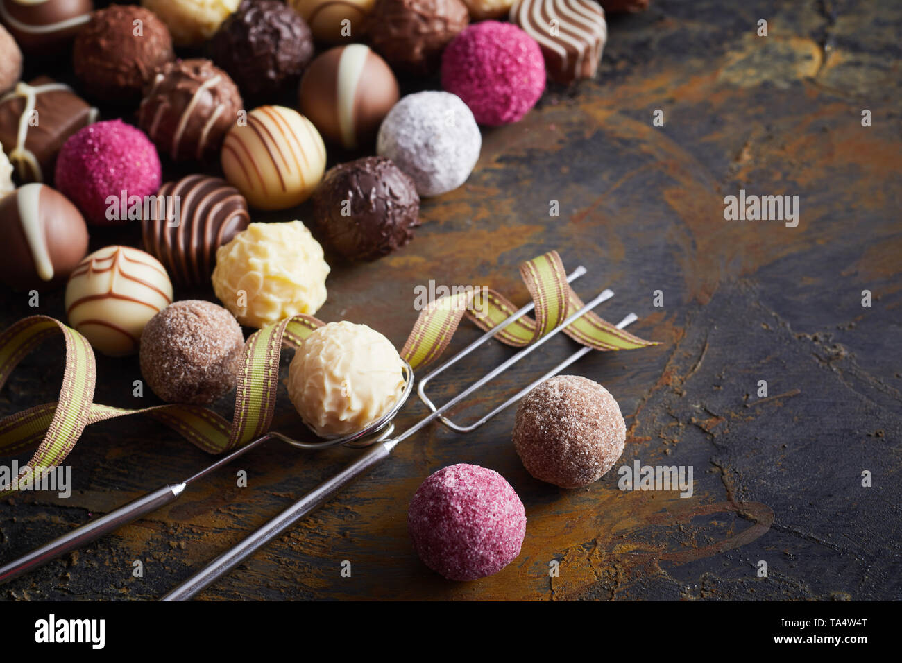 Un assortiment de chocolat de luxe fait main décorative bonbons boules ou avec fil vintage fourchette et lifter sur de vieux bois rustique pour une occasion spéciale ou valentin Banque D'Images