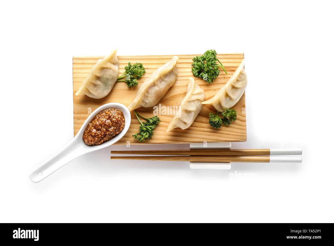 Support en bois avec de savoureux gyoza japonais sur fond blanc Banque D'Images