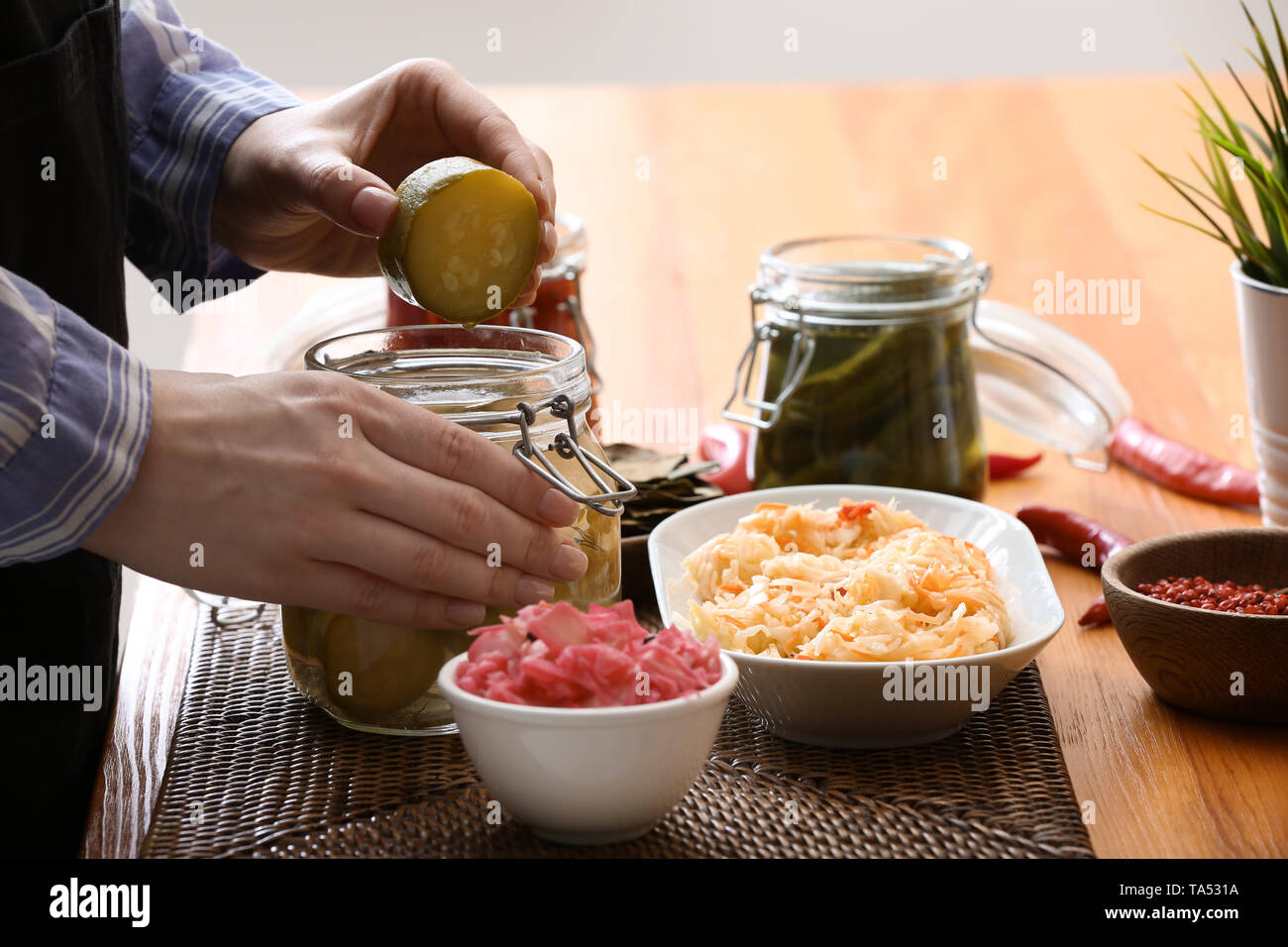 Femme avec de savoureux légumes fermentés dans la cuisine Banque D'Images
