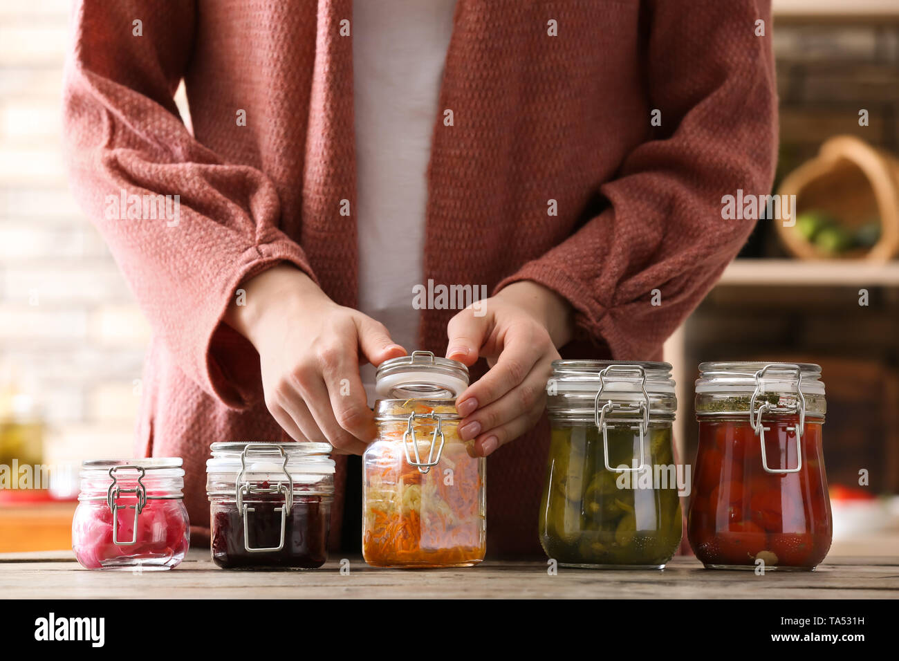 Femme avec de savoureux légumes fermentés dans les pots sur la table Banque D'Images