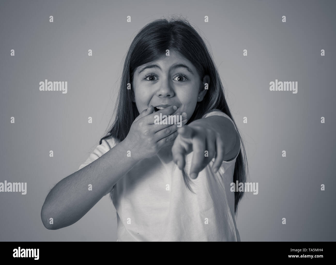 Portrait of Cute heureux, excité, drôle, souriant d'une jeune fille choquée surpris face à pointer du doigt quelque chose de bon et inattendu. Dans enfant Banque D'Images