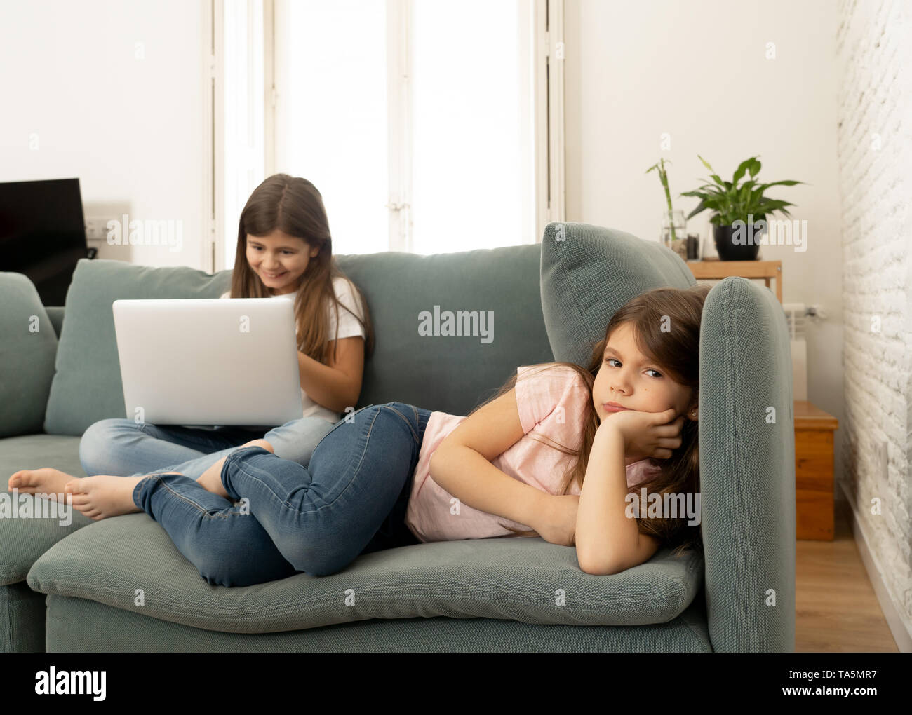 La technologie numérique addicted jeune fille jouant sur internet à l'aide d'ordinateur portable l'ignorant triste petite sœur. Petite fille se sentir abandonné et malheureux Banque D'Images