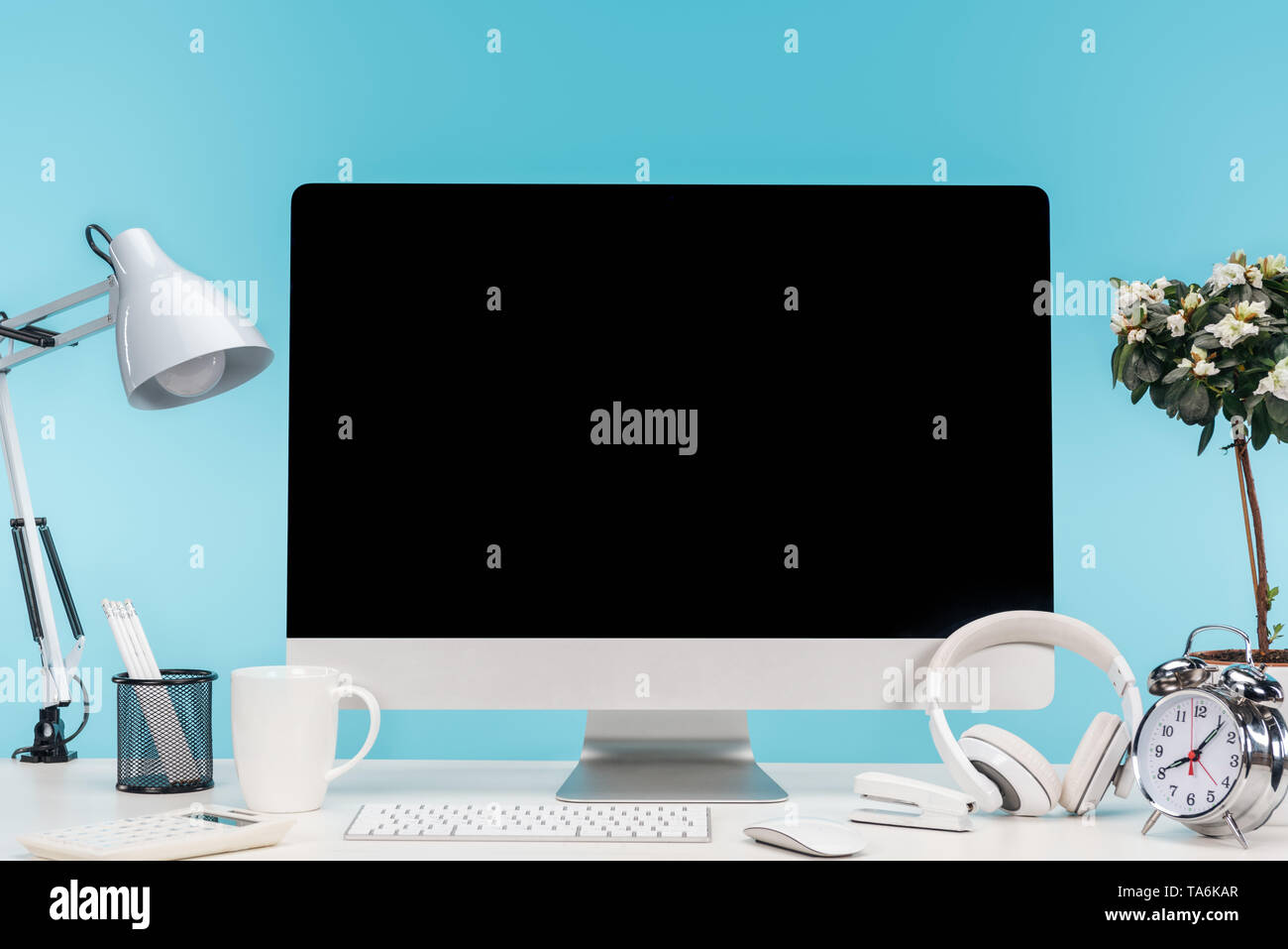 Lieu de travail avec ordinateur, lampe, papeterie et casque sur tableau blanc sur fond bleu Banque D'Images