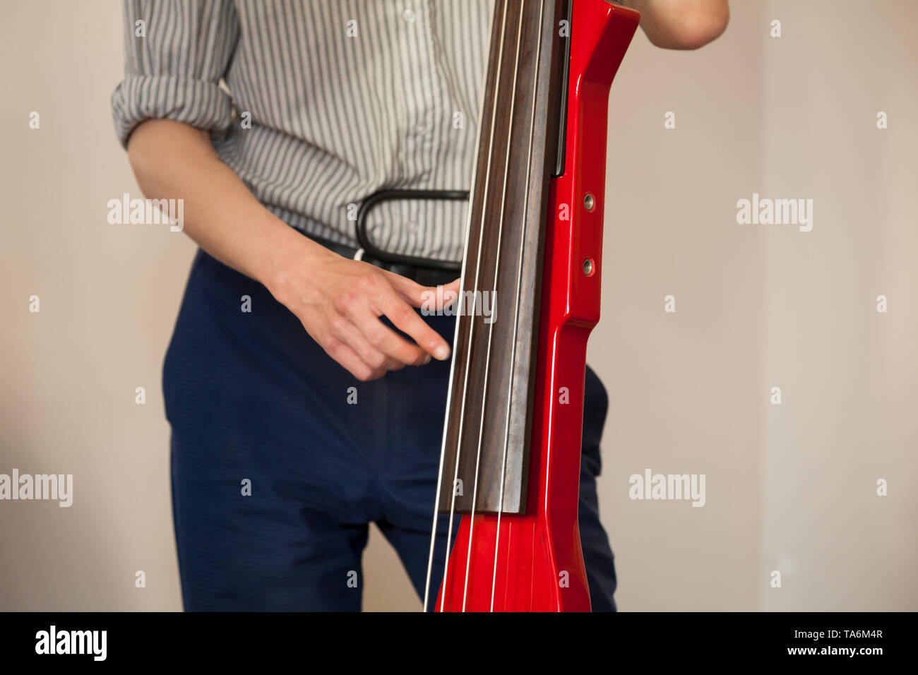 L'homme joue dans contrebasse électrique moderne rouge studio de musique Banque D'Images