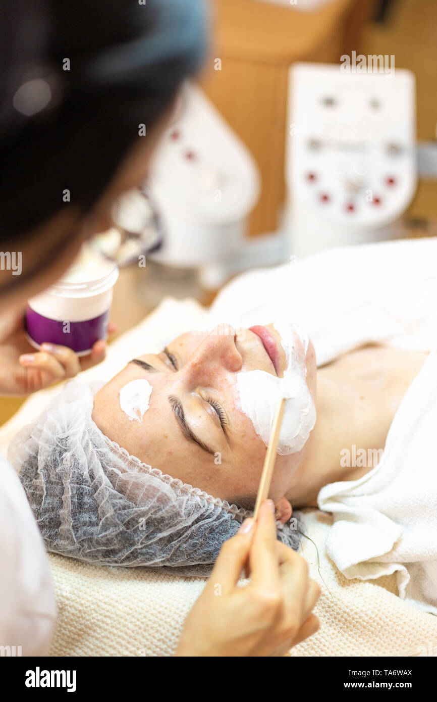 Woman getting facial care par boucher au spa beauté. L'application Cosmetologist masque sur du visage en spa salon Banque D'Images