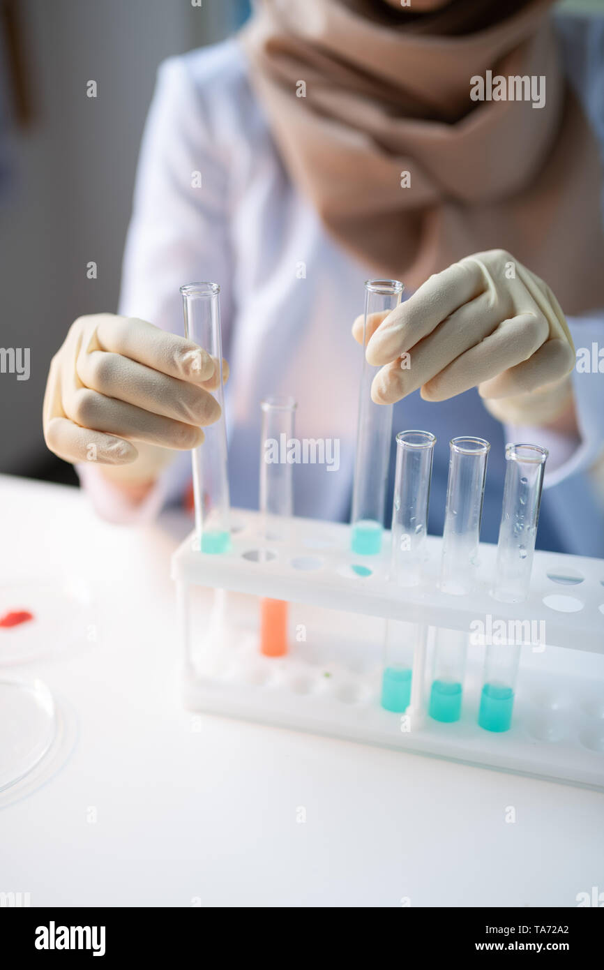 Close up du chimiste dans les gants en tubes à essai avec des produits chimiques Banque D'Images