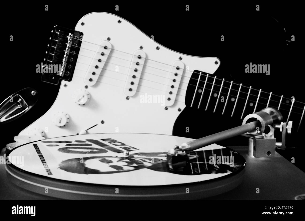 Le noir et blanc close up of record player avec disque vinyle et guitare électrique à fond noir Banque D'Images