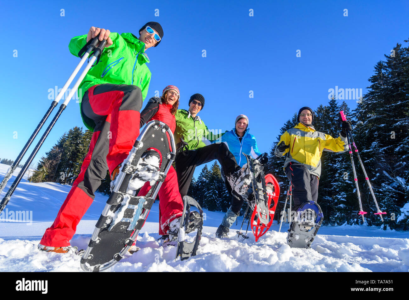 Un groupe de bonne humeur des gens qui font un tour en raquettes à la nature à un hiver froid et ensoleillé jour Banque D'Images