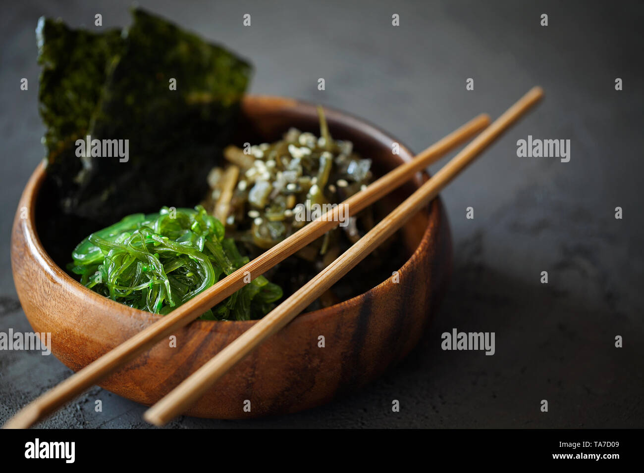 Snack traditionnel japonais - Chuka algues Wakame salade et feuilles nori rôti croustillant au bol en bois sur fond sombre avec copie espace pour le texte Banque D'Images