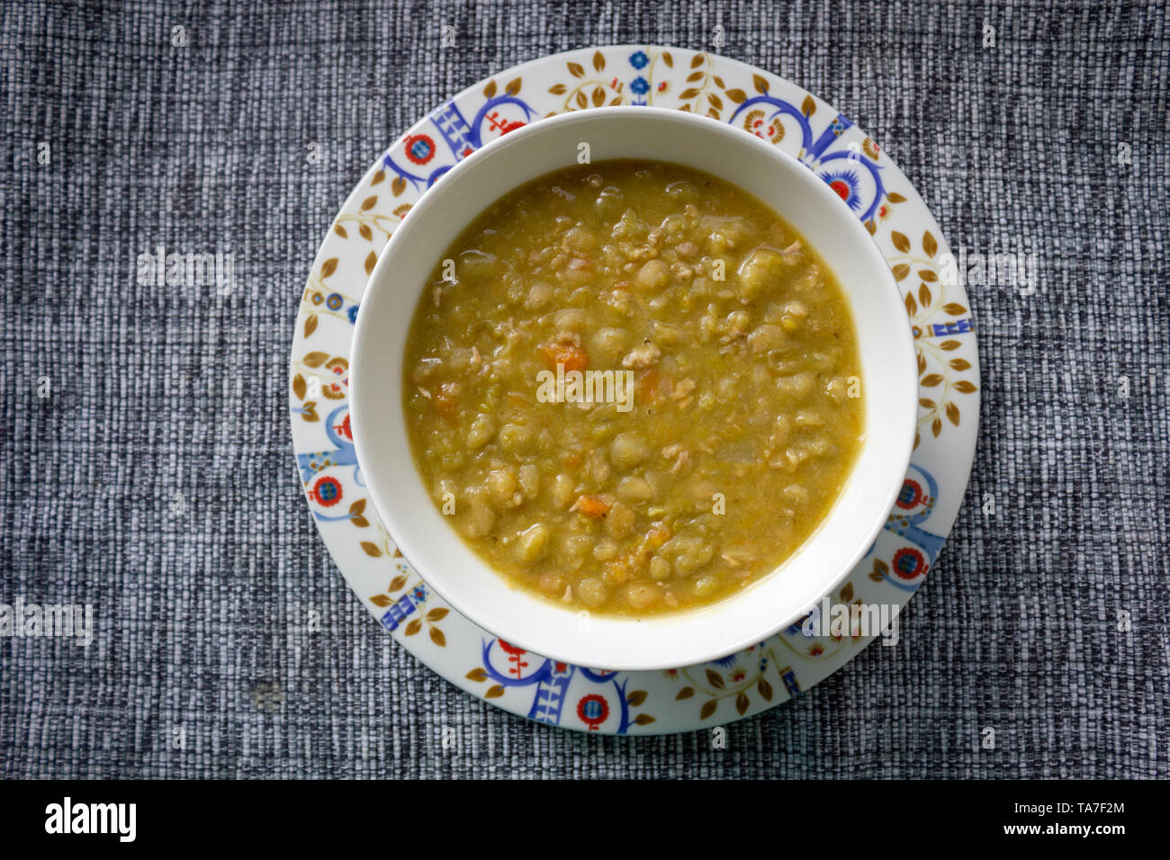 Soupe aux pois traditionnelle finlandaise sans viande sur une belle assiette, bol finlandais et tapis de table Banque D'Images