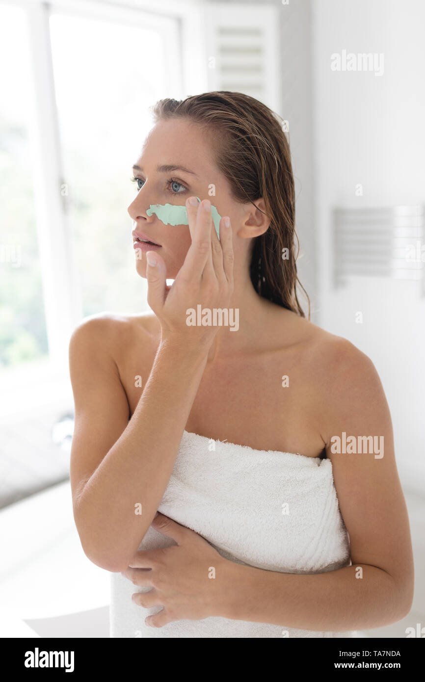 Woman applying facial mask après avoir baignoire Banque D'Images