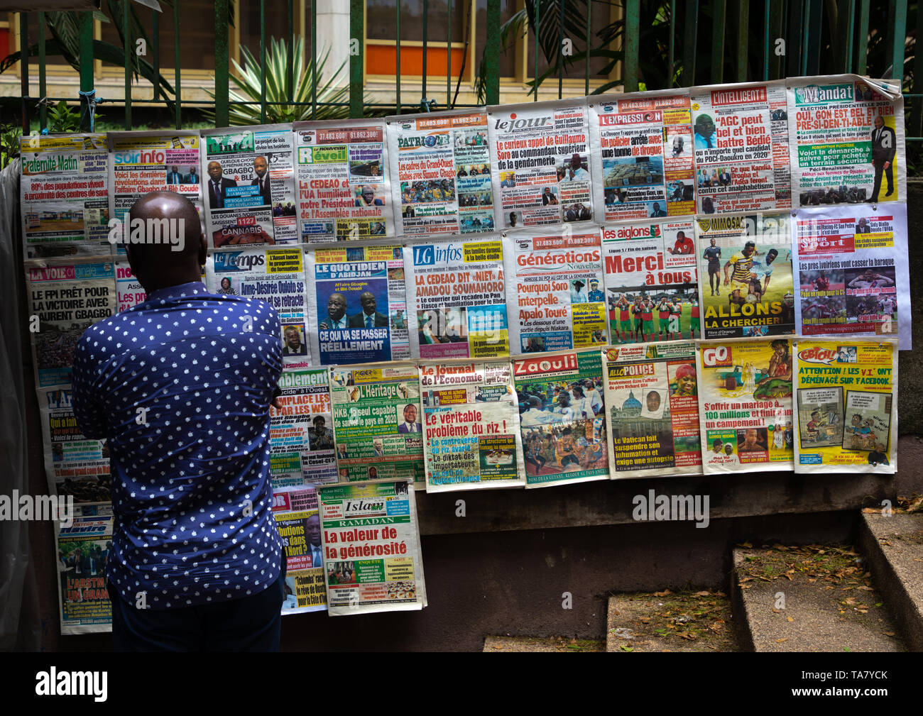 Homme africain lire les journaux affichés sur un étal de marché, Région des lagunes, Abidjan, Côte d'Ivoire Banque D'Images