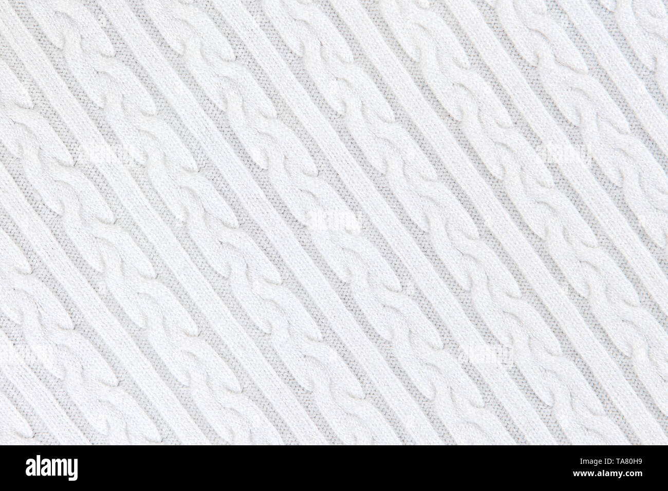 Texture Tissu tricot avec des nattes et de rayures. Tricot Machine répéter la texture de chandail. Tricot blanc Arrière-plan. La composition en diagonale. Banque D'Images