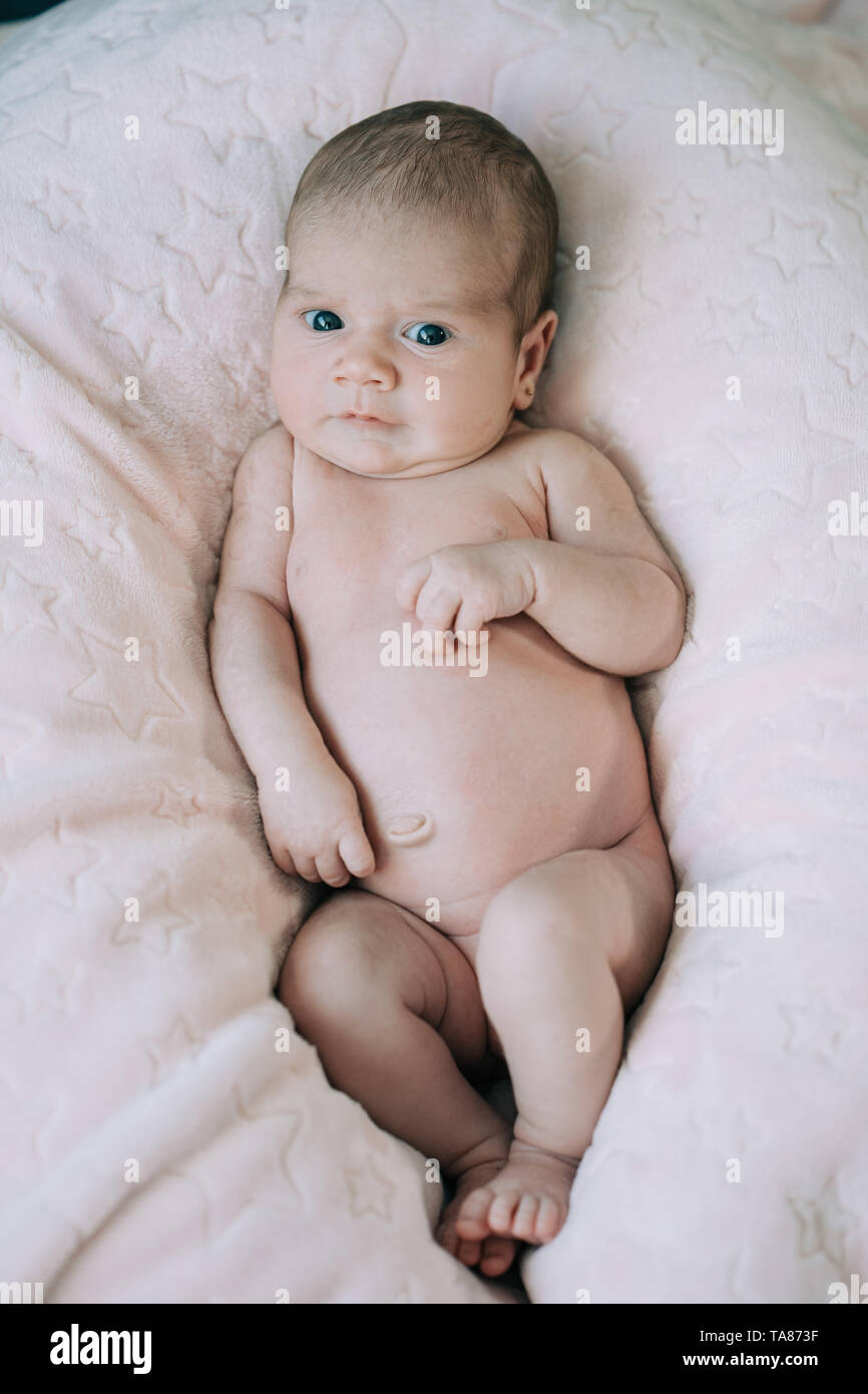 Cute adorable bébé nouveau-né fille dans un lit et enveloppé dans une couverture rose. Nouveau-né, petite fille à la surprise de l'appareil photo. Famille, vie nouvelle, Banque D'Images