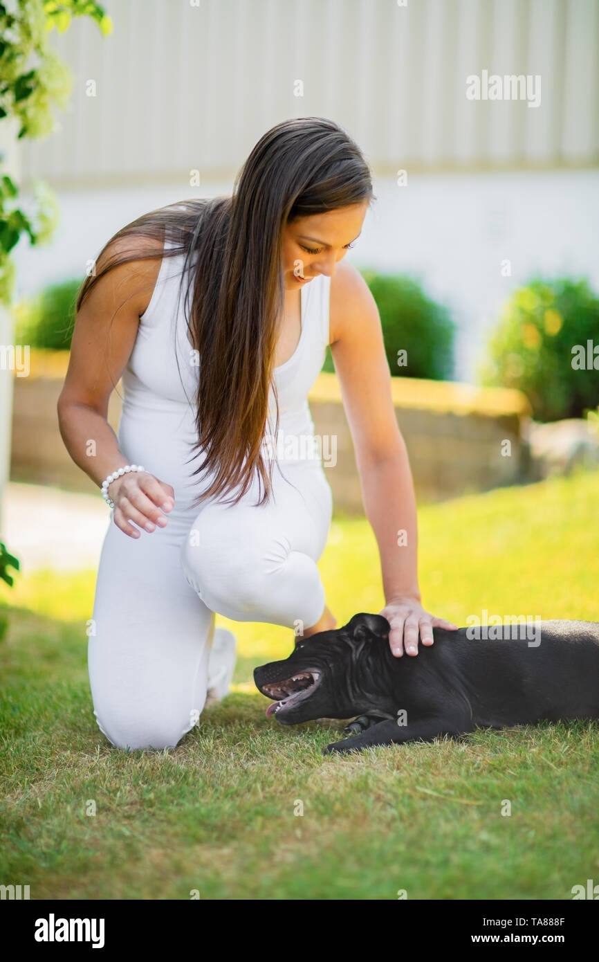 Smiling femme enceinte avec un gros ventre tape son chien dans le jardin Banque D'Images