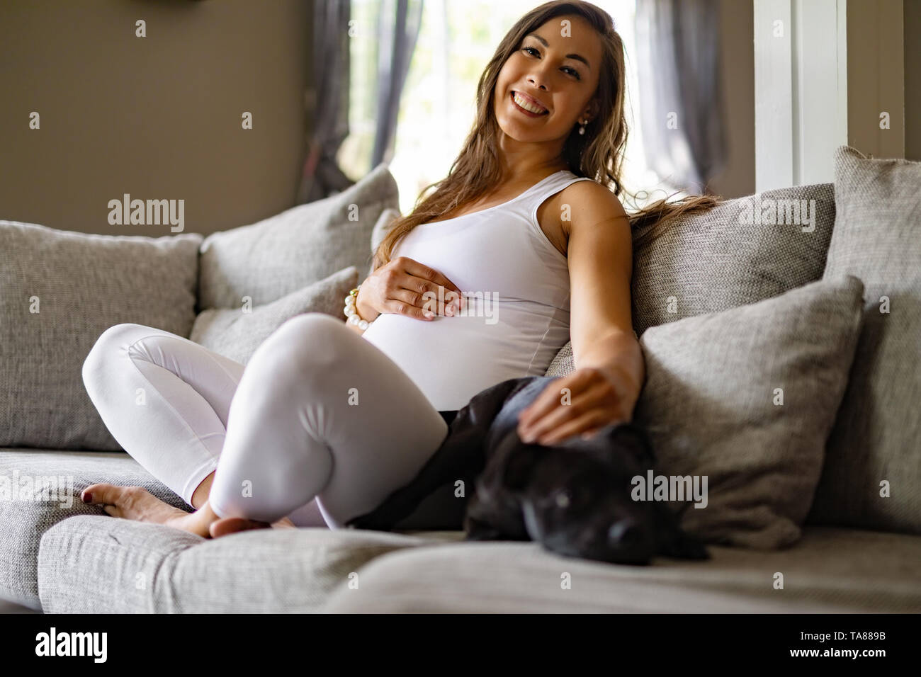 Happy pregnant woman sitting in canapé et son chien pet Banque D'Images
