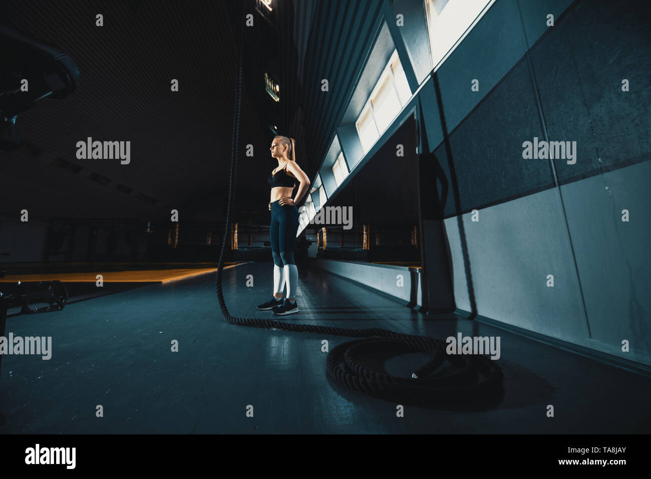 Prise de vue au grand angle sur toute la longueur de la corde de la scène une femme monte dans la salle de sport. Copyspace contexte avec l'athlétisme composition saine. Crossfit et cent Banque D'Images