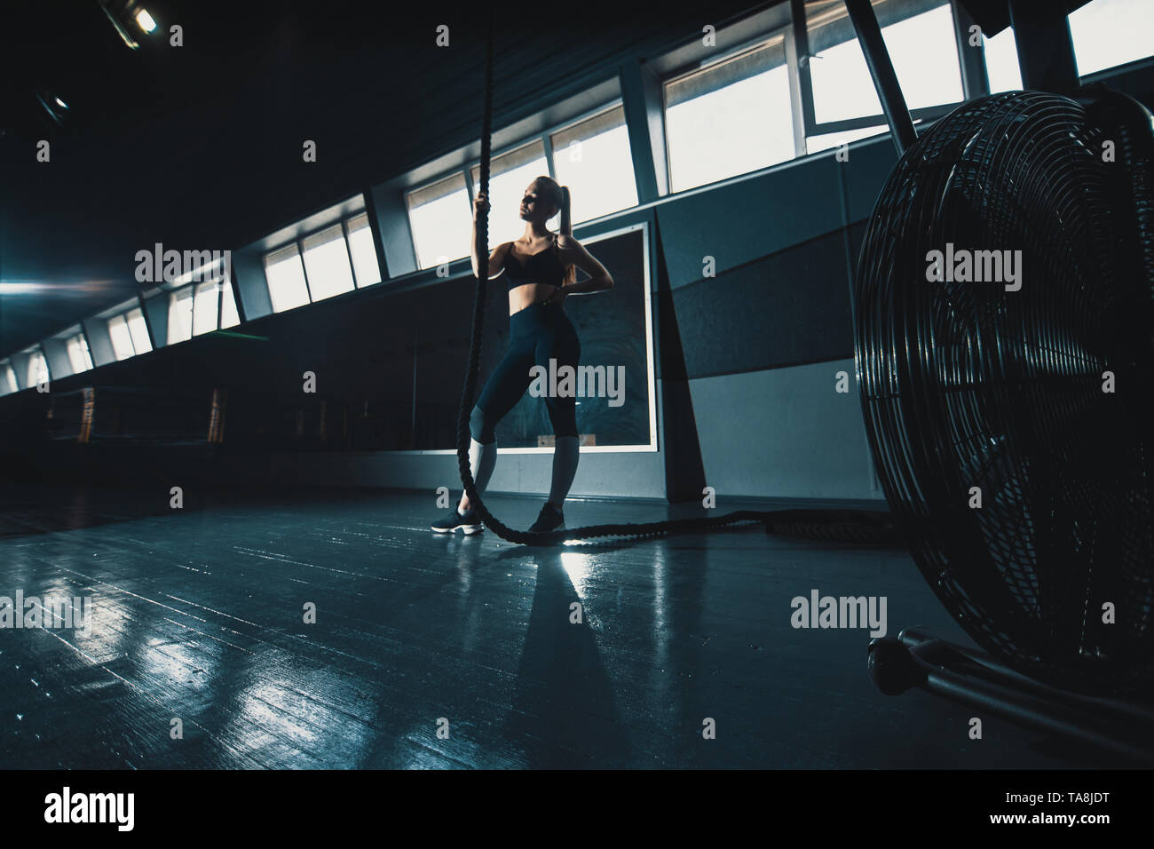 Prise de vue au grand angle sur toute la longueur de la corde de la scène une femme monte dans la salle de sport. Copyspace contexte avec l'athlétisme composition saine. Crossfit et cent Banque D'Images