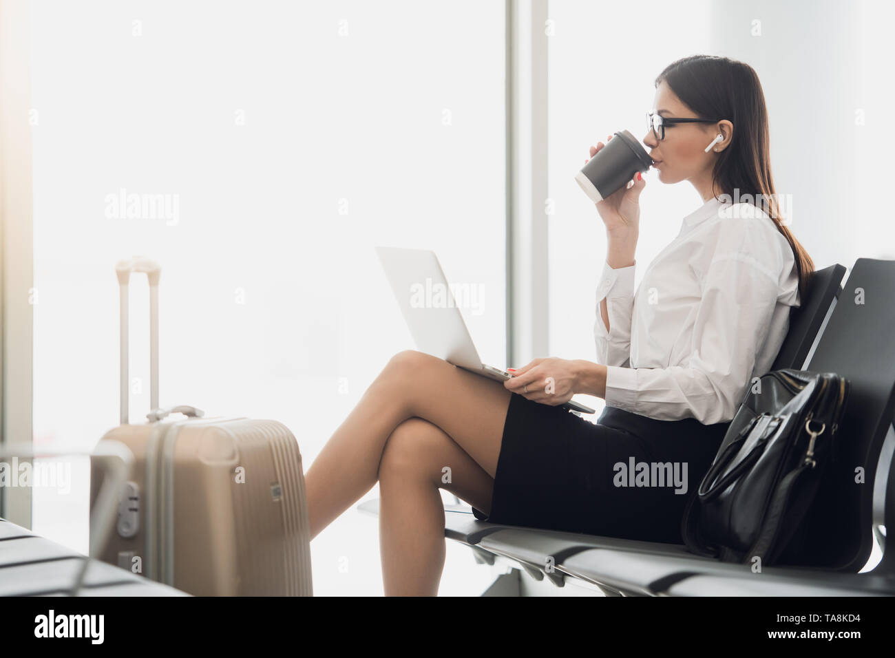 Young businesswoman dans l'aéroport, à l'aide d'ordinateur portable et de boire du café, voyage, voyage d'active et en concept Banque D'Images