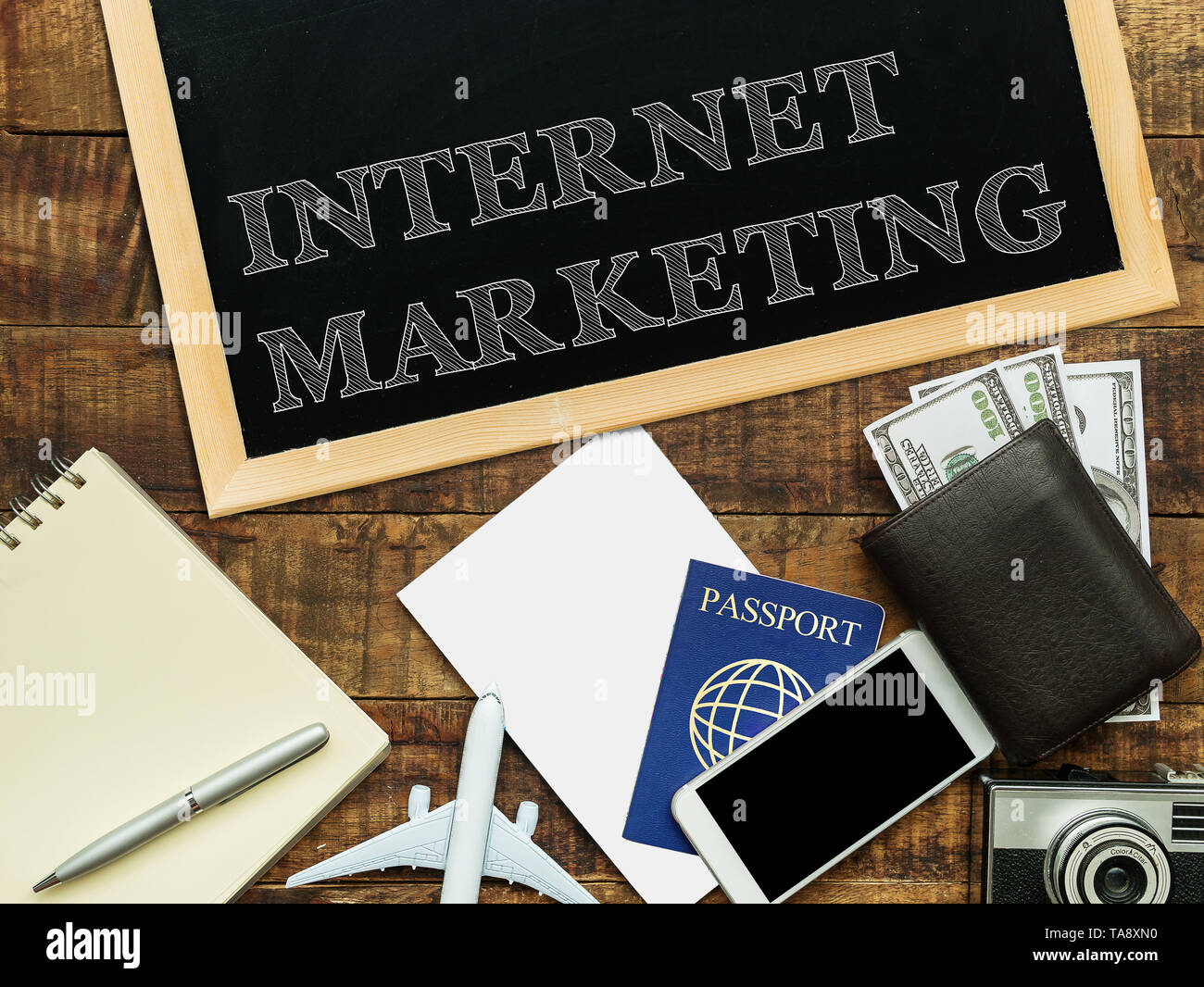 Le marketing internet à la main avec craie blanche sur un tableau noir, portefeuille monnaie , ordinateur portable et smartphone sur un fond de bois Banque D'Images