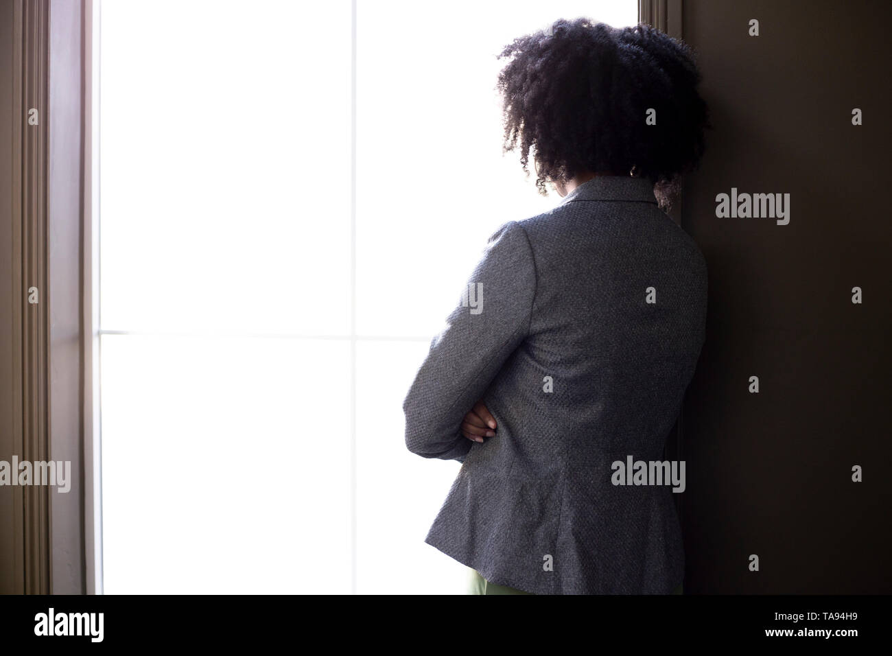 Silhouette d'un stressé black African American businesswoman smiling et réfléchir aux problèmes et l'échec par la fenêtre du bureau. Elle l Banque D'Images