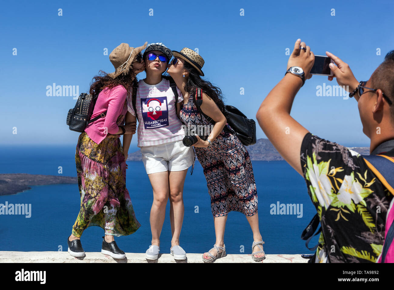 Touristes Santorini trois femmes dans un endroit célèbre en Grèce touristes prenant photo au-dessus de la mer, îles grecques tourisme en Europe Banque D'Images
