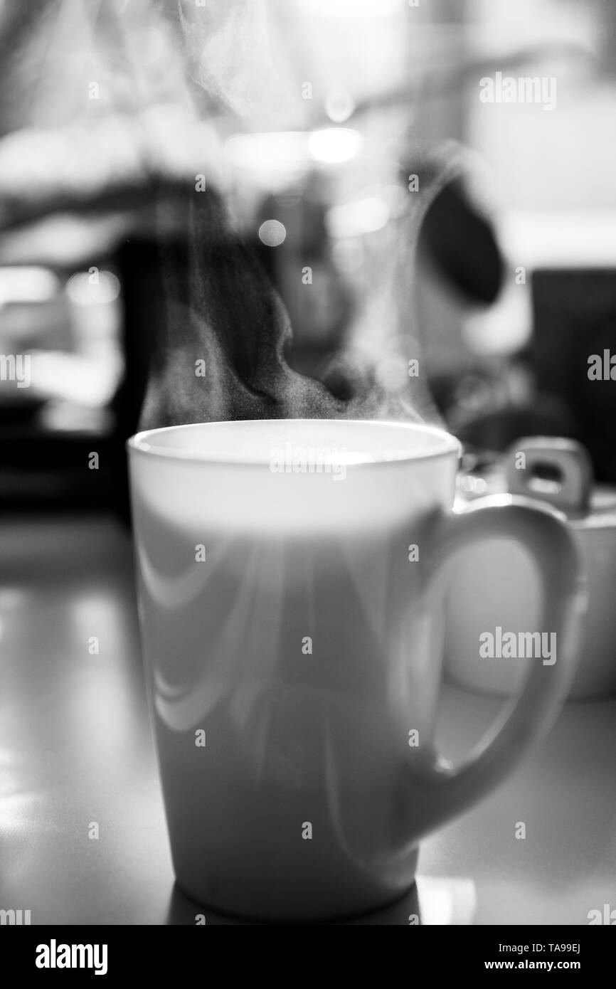 Tasse de thé blanc café sur table avec des particules minuscules de la vapeur à vapeur noir et blanc Banque D'Images