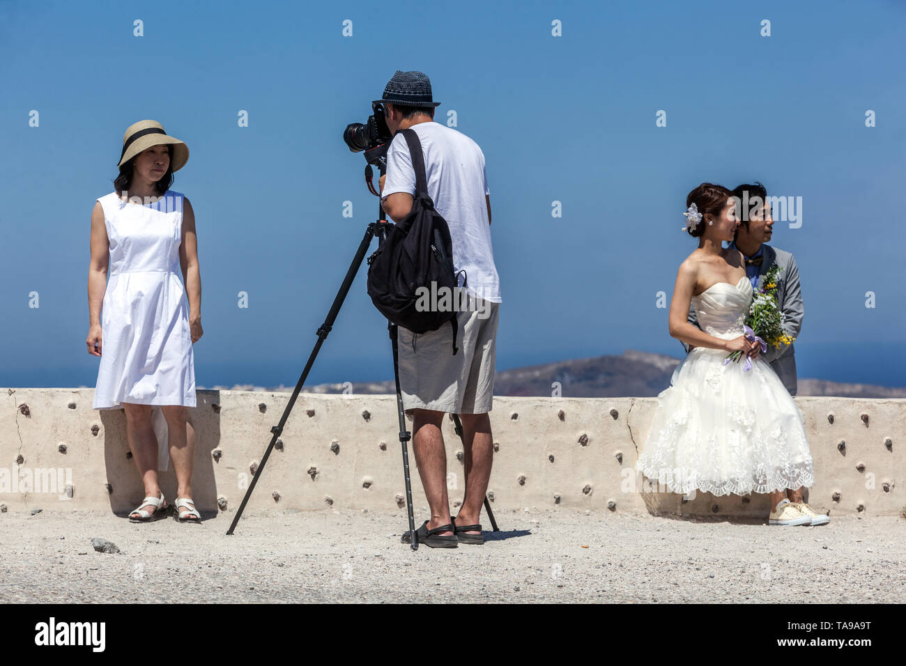 Santorin, les touristes au-dessus de la mer sur la terrasse, faire de l'homme photo avec trépied. Les jeunes mariés juste asiatiques, Grèce Europe Banque D'Images